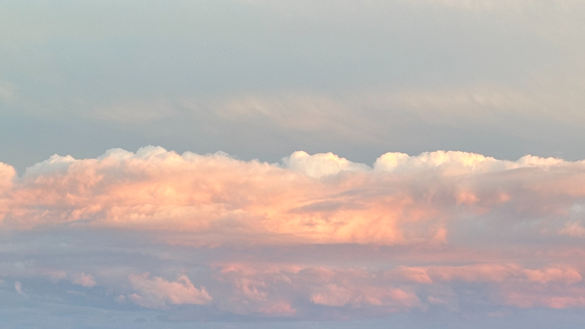Pink, orange and white clouds against a whispy blue sky